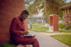 a man sitting on a sidewalk reading a book